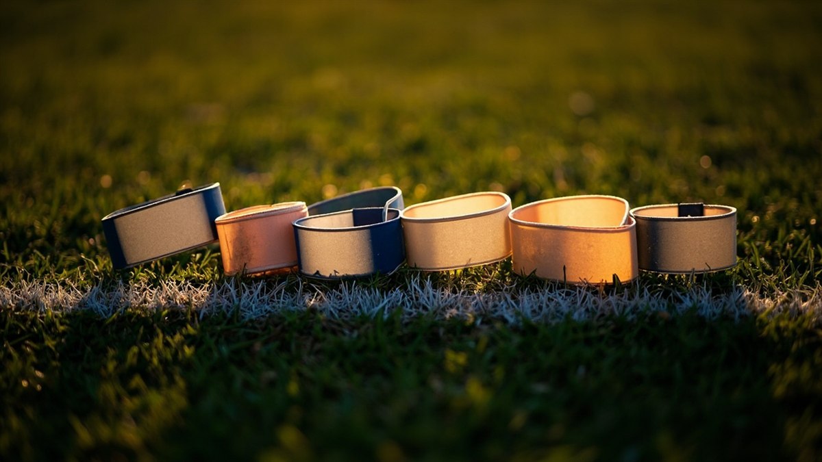 Five captain armbands laid out in a row on the touchline at dawn