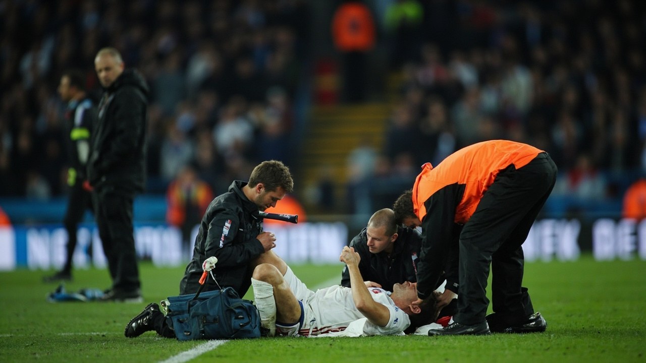 England forward receiving treatment on the touchline at the Etihad during a friendly under floodlights, medical staff crouched in attendance, crowd blurred behind the advertising.